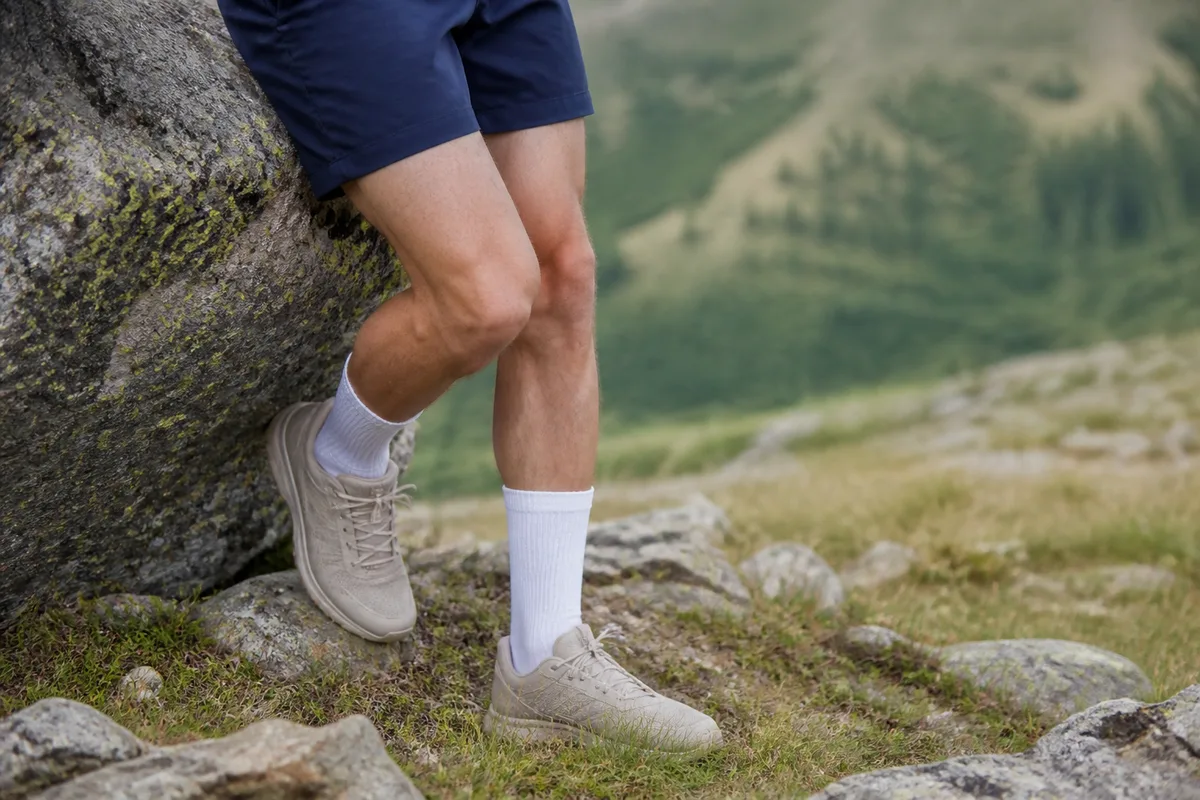 Jambes de coureur à l&rsquo;arrêt appuyées contre un rocher au bord d&rsquo;un sentier