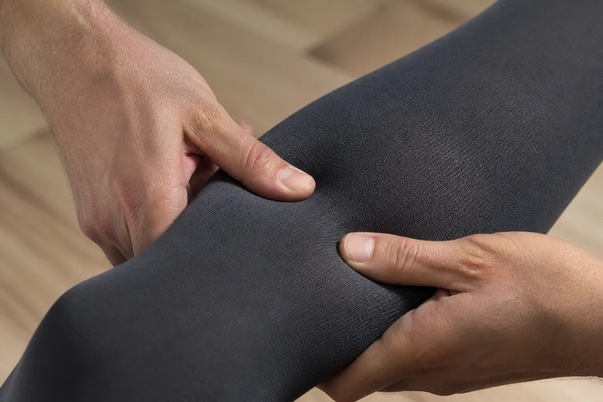 Mains massant un mollet à travers une chaussette de compression